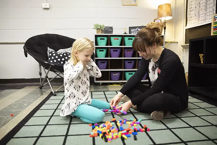 a SEMO education student sits with a child and plays with building blocks
