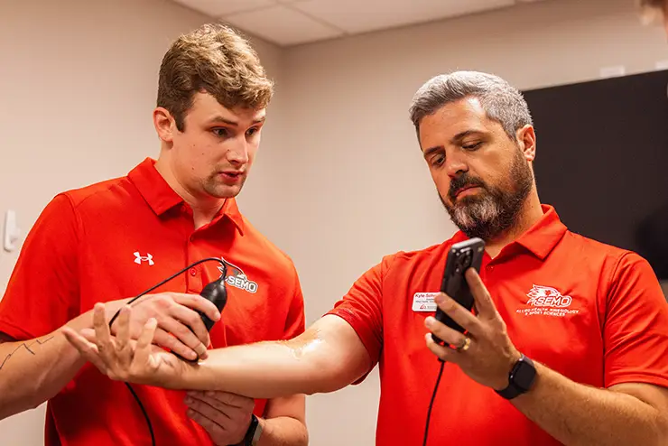 an athletic training student practices taking an ultrasound of an instructor's arm