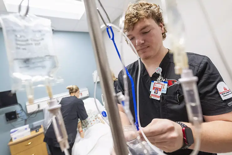 a nursing major prepares an IV bag for a patient