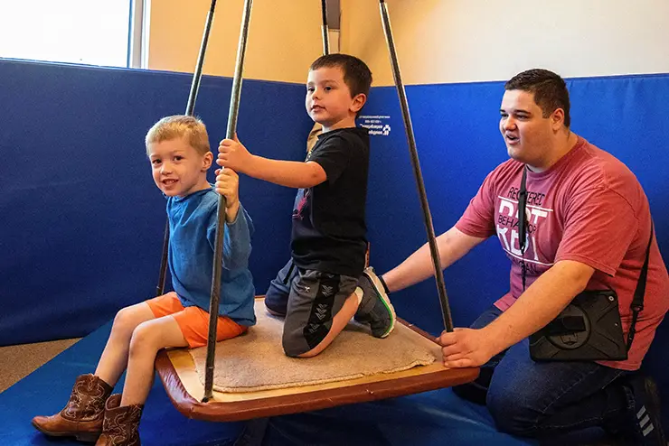 a SEMO communication disorders student works with two children in the autism center