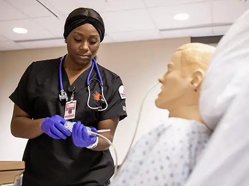 a SEMO nursing student practices using an IV line on a manikin in the nursing lab
