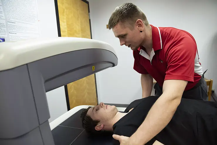 a health sciences student practices using a piece of equipment in the health sciences lab