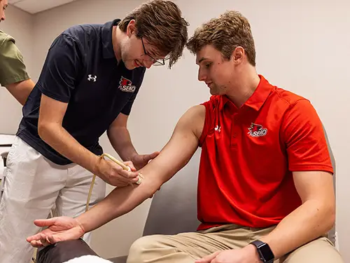 an athletic training student practices searching for a vein