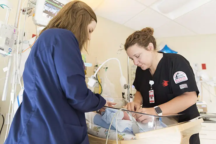 a nursing student and a saint francis nurse work together on a newborn in labor and delivery