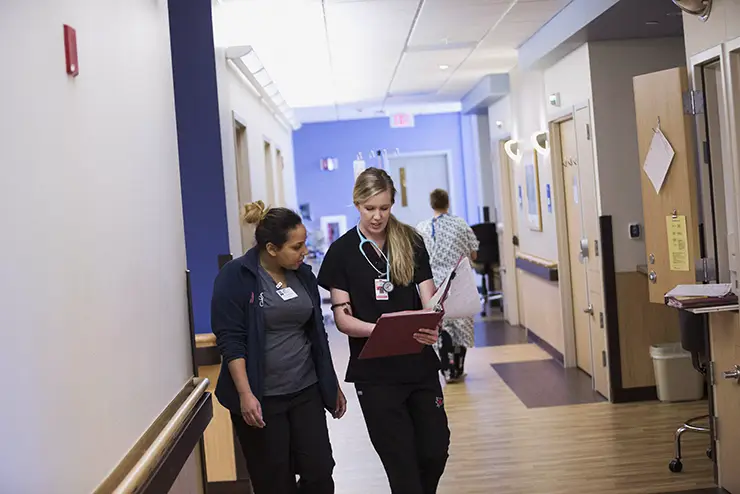 a SEMO nursing student pauses to ask a question of her supervisor in a hospital hallway