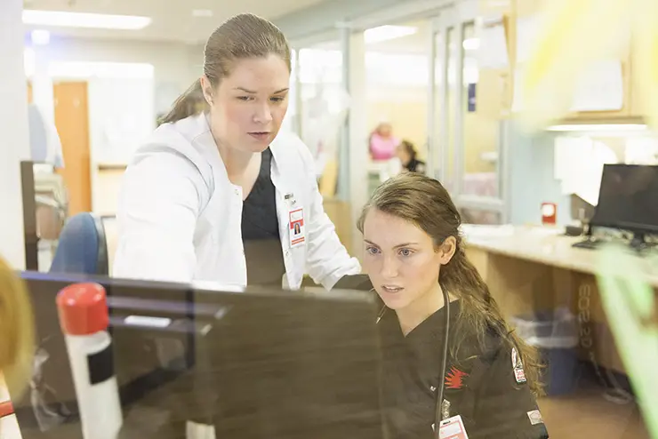 a SEMO nursing student works at a hospital computer with a supervisor