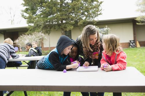 During their student teaching experience, a Southeast student interacts with students at a picnic table at Jefferson Elementary 