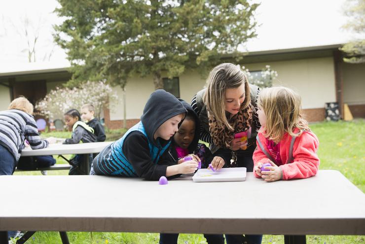 During their student teaching experience, a Southeast student interacts with students at a picnic table at Jefferson Elementary 