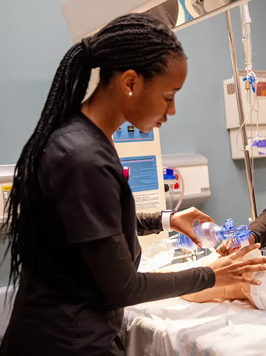 nursing students perform exams and use a breathing apparatus on a manekin