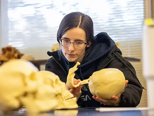 anthropology student in a lab closely examining materials for her coursework getting hands on learning at SEMO a Missouri college known for job readiness 