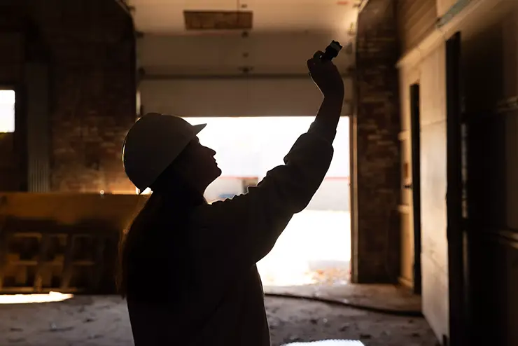 a silhouetted student in a hard hat uses a flashlight to examine a local historic building at semo a Missouri college known for job readiness