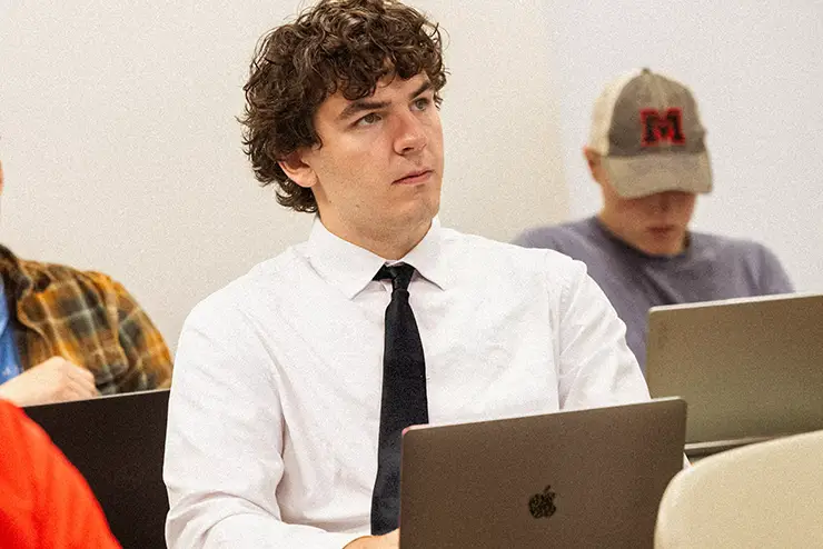a student in shirt and tie sits at a desk with his computer during a lecture at semo a Missouri college known for job readiness
