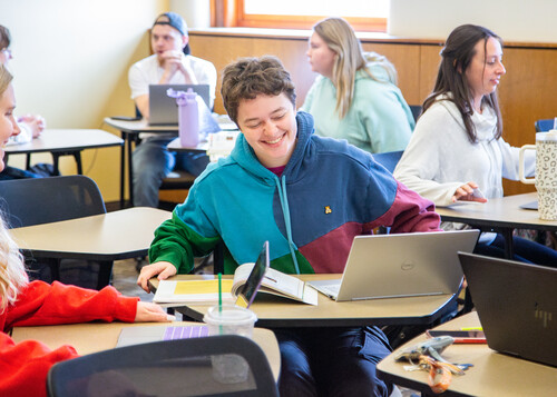 A communication studies student laughs in a group while in class.