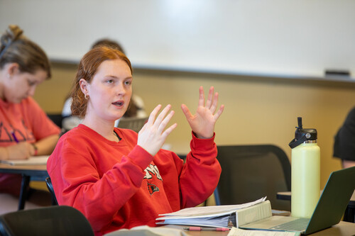 A student gestures while asking a question during class.