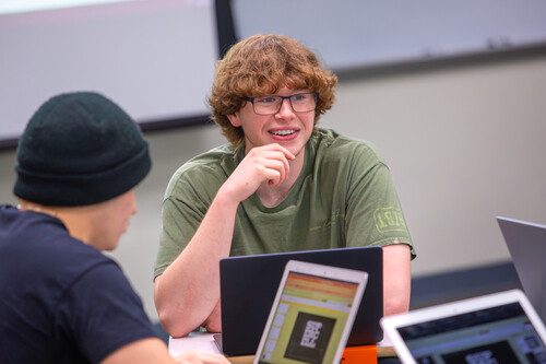 A student smiles across the table during a discussion in a business class.