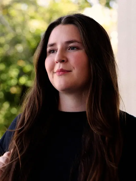 portrait of emilie standing on the Kent Library portico with tress blurred out behind her