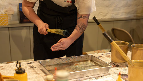 Participant of the historical preservation field trip paints using a water method.