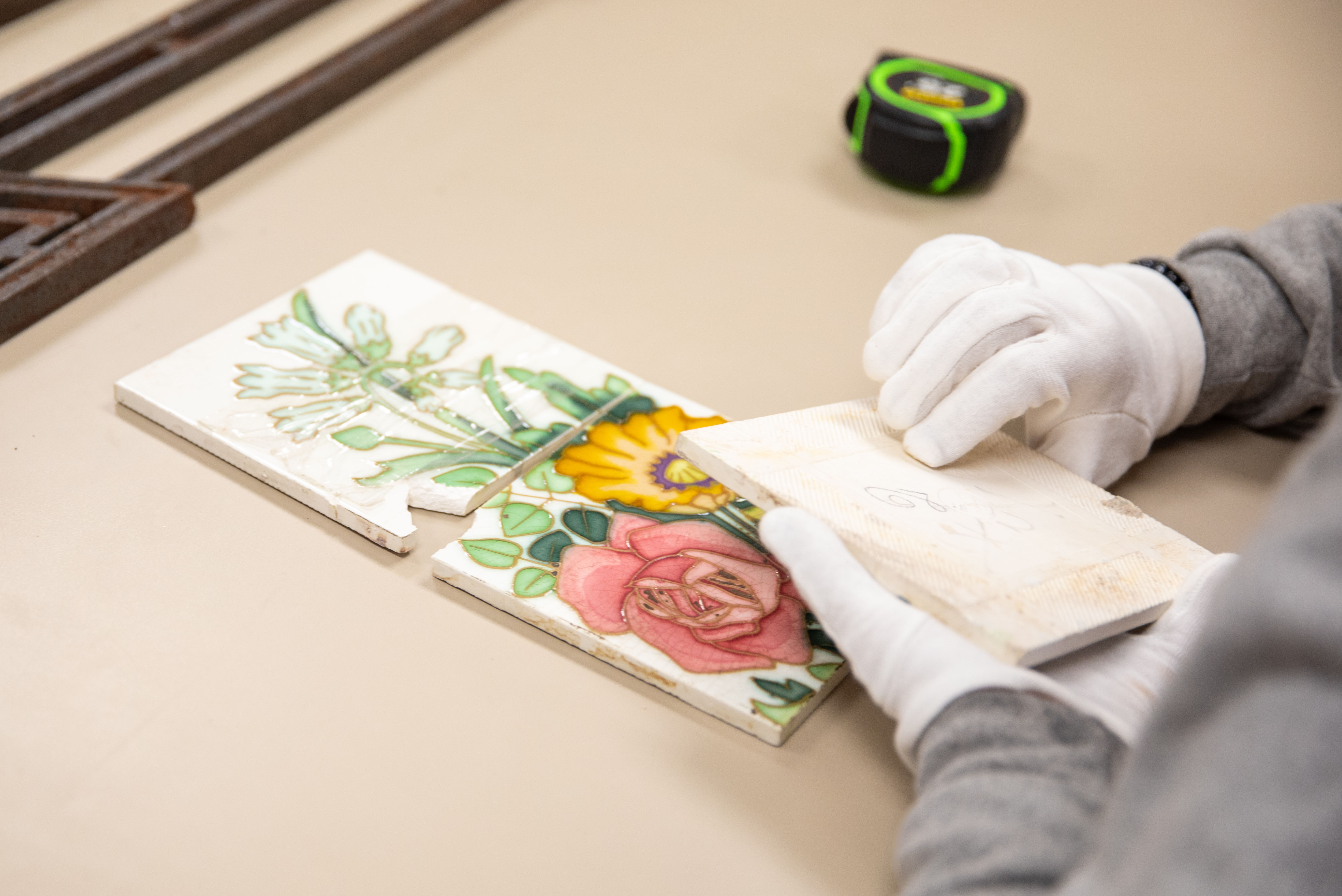 an historical preservation student works on a flower slab that is chipped.