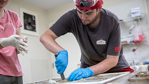Participant of the historical preservation field trip works on a window.