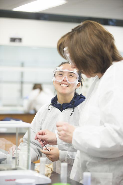 A chemistry student smiles while working with a peer in a lab in Magill Hall.