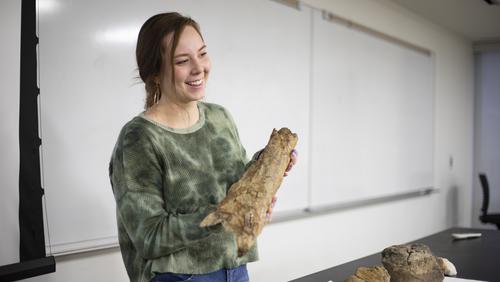 A geoscience student displays an object while presenting findings from a Montana summer camp.