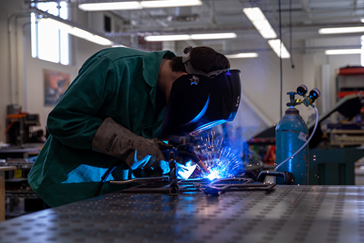 a faculty member and a student at the SEMO farm stand next to a piece of equipment and talk