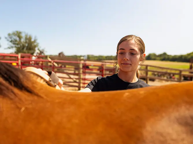 Lacey, an agriculture animal science student, at the David M Barton Agriculture Research Center brushing a horse
