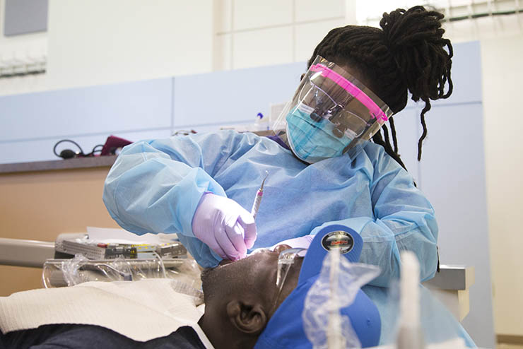 a dental student works on a patient's teeth