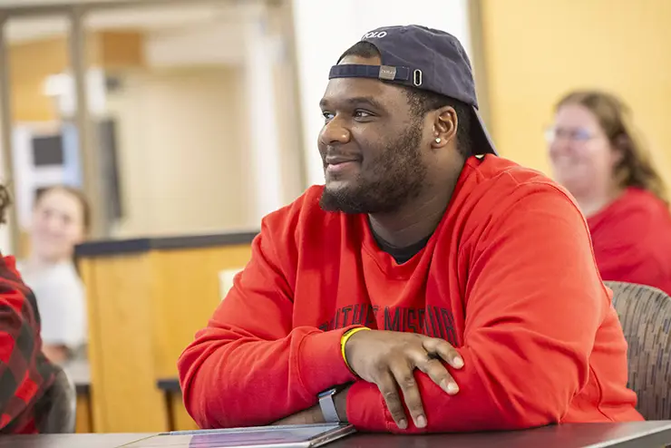 a SEMO student sits in class smiling and listening to the instructor