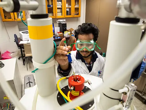 a chemistry major works with a piece of equiment during his research