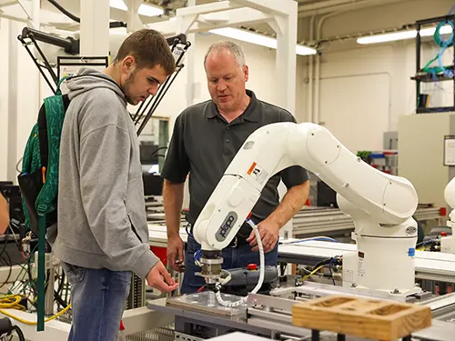semo engineering students work with a professor on using a robot arm in the lab