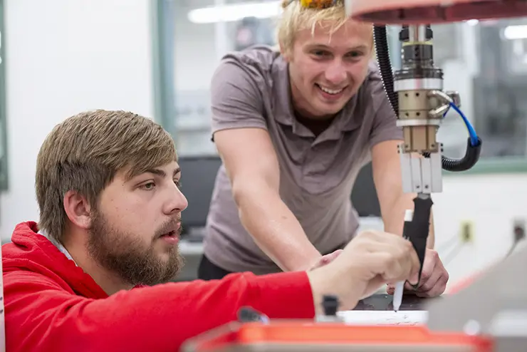 two SEMO mechanical engineering majors work with a piece of shop equipment