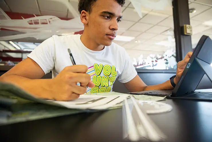 a SEMO professional pilot student plots out a flight course on a map
