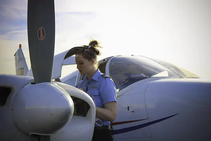 a SEMO aviation student checks on the engine of the plane she's about to fly