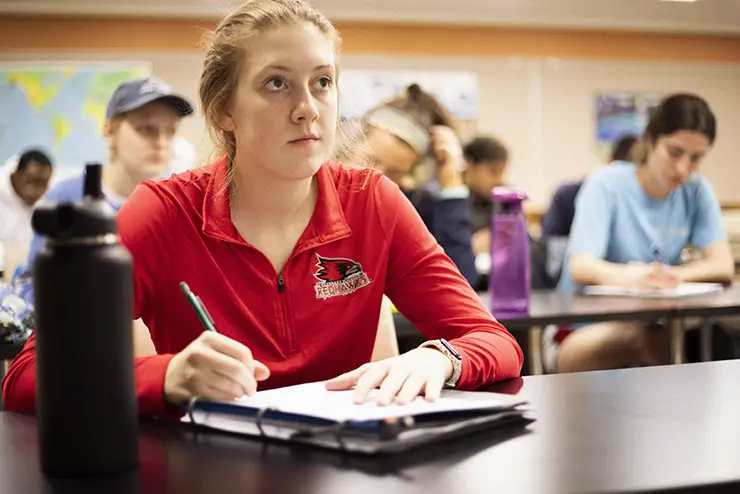 a mathematics student sits in class taking notes