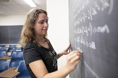 a math major works at the black board writing out equations