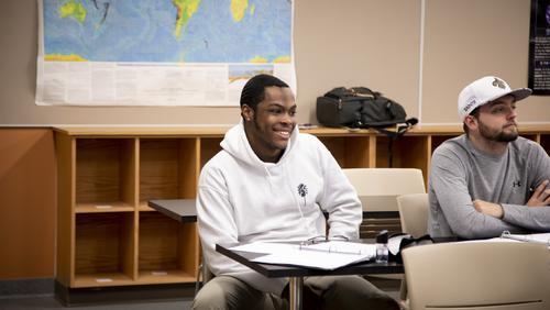 Mathematics students sit at their desks listening to a lecture.  