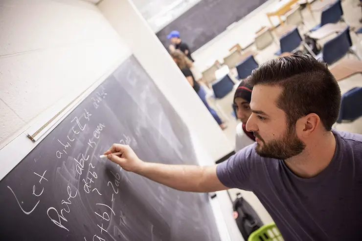 a SEMO mathematics student works an equation on the chalkboard