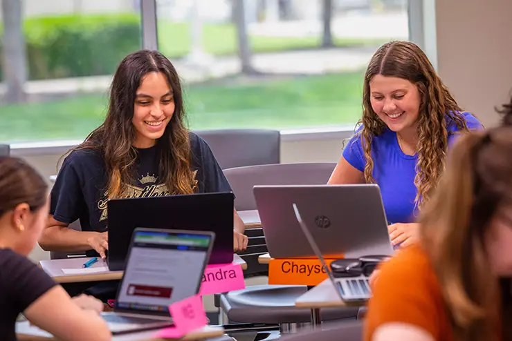 students sit in a group during class working on a project
