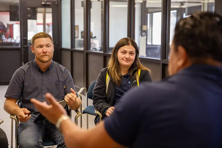 two students participate in a training, listening to the instructor