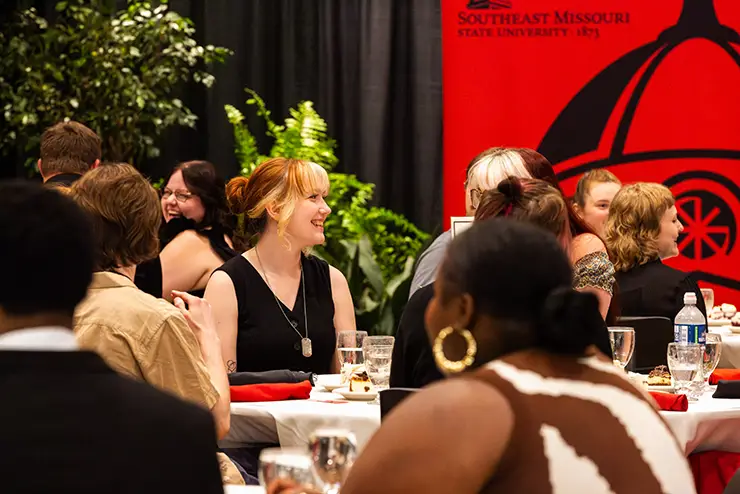 a student dressed up for an event sits at a elegantly set table during an event