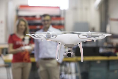 A male and female student fly a drone.