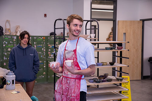 a SEMO ceramics student holds un-fired ceramic bowls