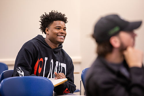 a SEMO student in a classroom smiles as he listens to the instructor