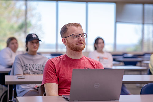 a SEMO business student is seated at a table with his laptop open in front of him
