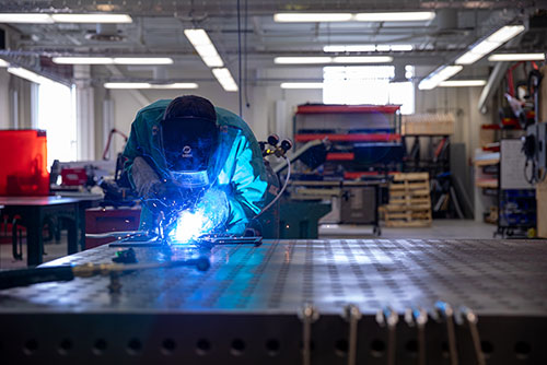 a SEMO student works in a workshop with a welder