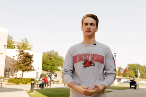 Elliot Siekmann stands in the courtyard in front of Johnson Hall on a sunny autumn day.
