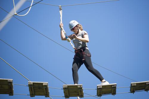 A student wearing safety gear navigates Recreation Services’ Challenge ropes course.