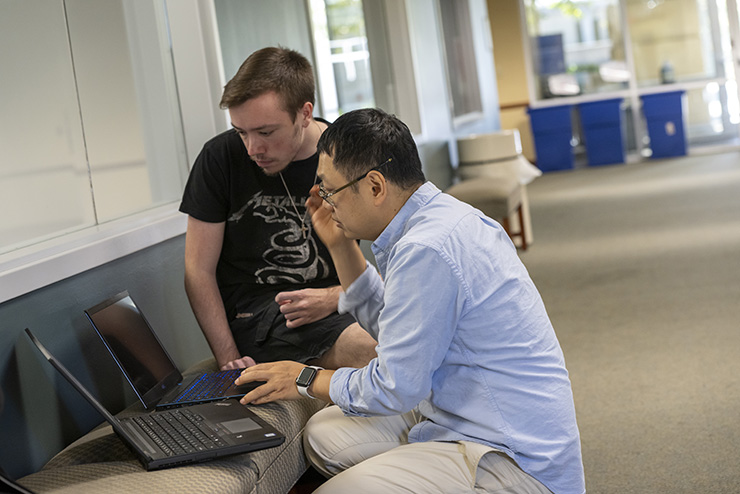 A SEMO computer science teacher takes time to g o over something with a student in the hallway of Dempster.