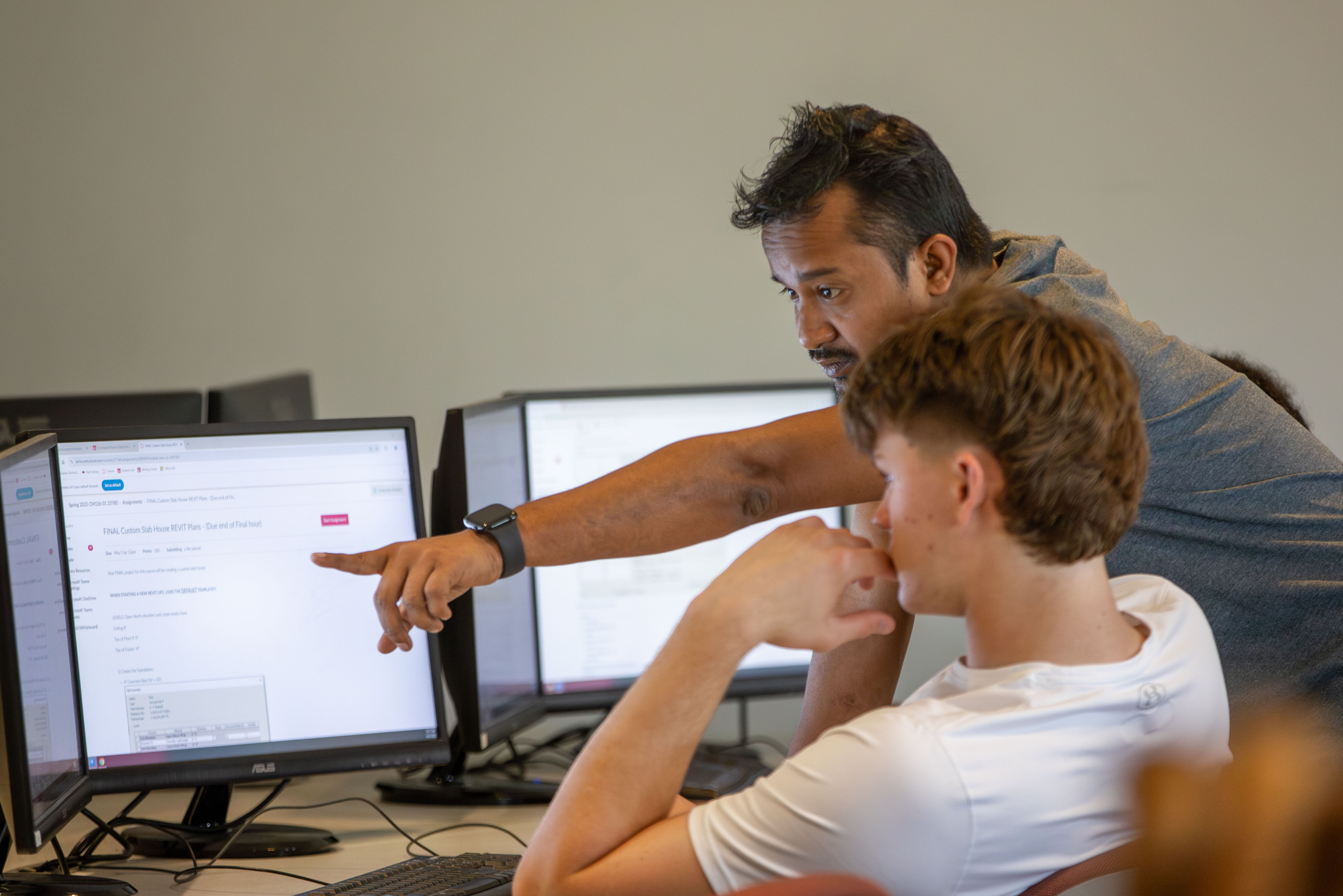 A teacher is pointing something out to a student during a drafting class.